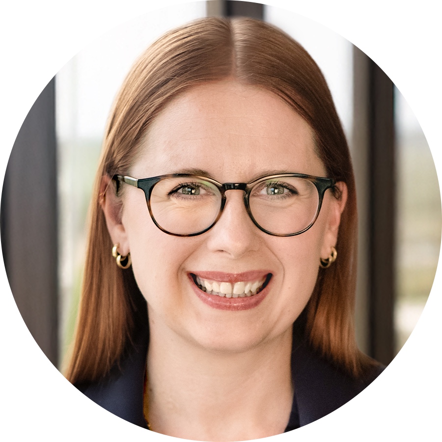 Headshot of Heather K. Strack in eyeglasses, smiling in a blazer with her hair behind her shoulders.